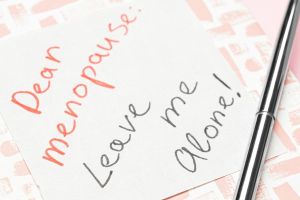 Handwritten note reading “Dear Menopause: Leave me alone!” next to a pen.