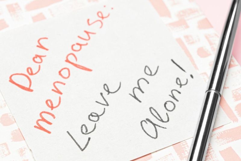 Handwritten note reading “Dear Menopause: Leave me alone!” next to a pen.