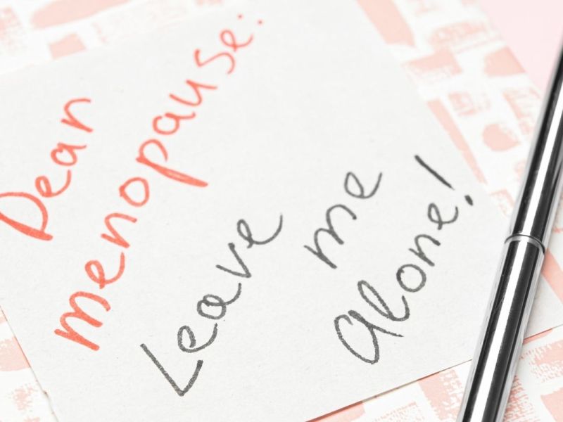 Handwritten note reading “Dear Menopause: Leave me alone!” next to a pen.