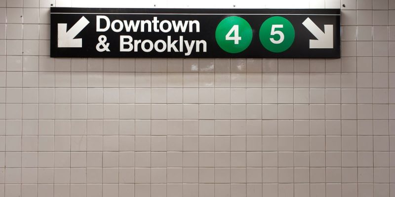 New York City subway sign pointing toward Downtown Manhattan and Brooklyn