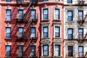 Classic New York City apartment buildings with fire escapes in a walkable residential neighborhood