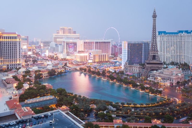 
Aerial view of the Las Vegas Strip at twilight featuring the Bellagio Fountains, Caesars Palace, Paris Las Vegas, and surrounding resorts.