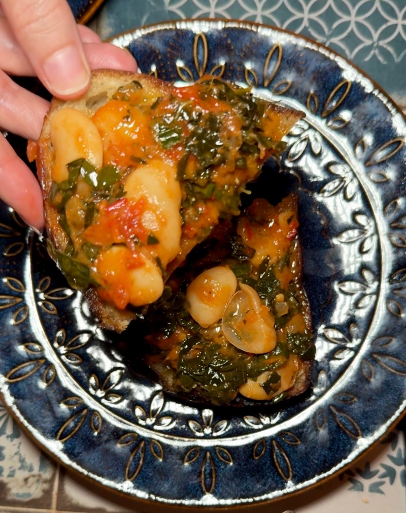 Toasted bread topped with butter beans, dark kale and heirloom tomatoes at Al-Anadalus